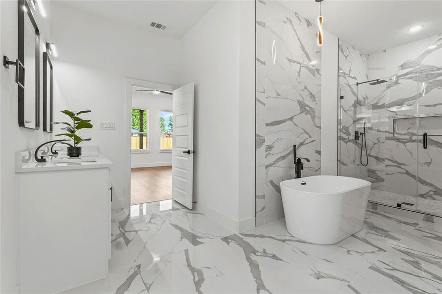 Bathroom with marble tiled floors, a marble finish shower, vanity, and a freestanding bath