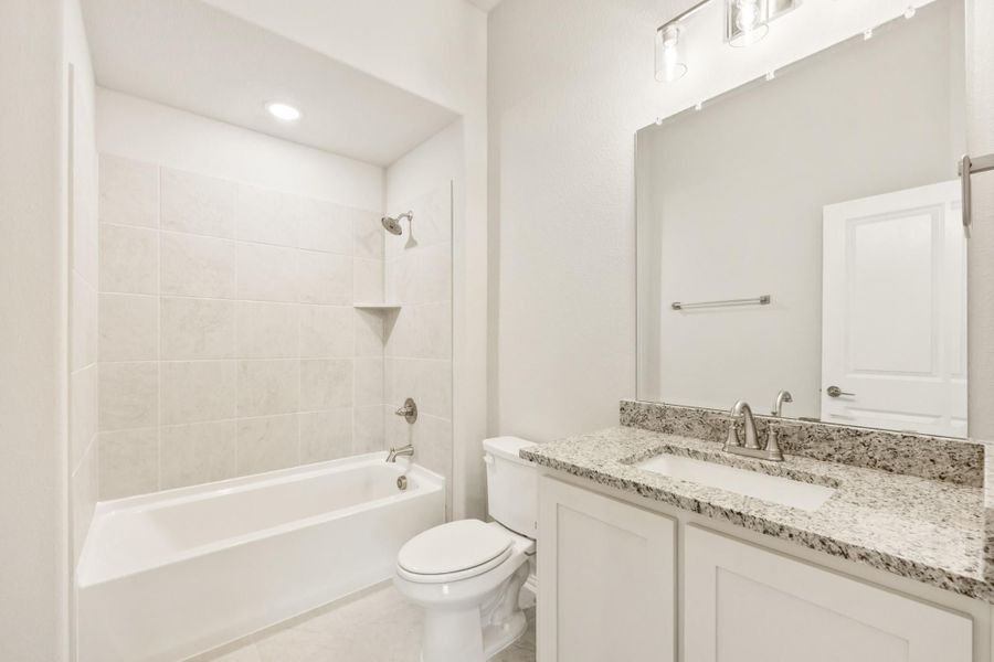 Bathroom with tiled tub-shower combo, white vanity with granite countertop, and large mirror Bathroom with tiled tub-shower combo, white vanity with granite countertop, and large mirror