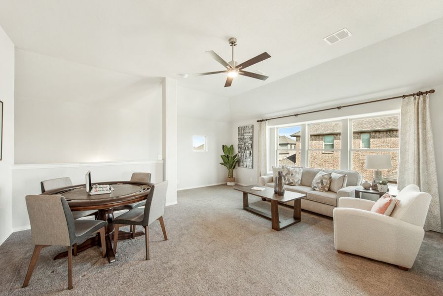 Open living and dining area with ceiling fan, carpet floors, and large windows