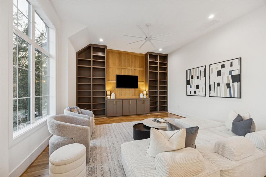 Designed as a true second living space, the upstairs game room offers flexibility for movie nights, play, or casual lounging. Custom built ins provide storage and display, while high ceilings and large windows keep the room bright and comfortable for everyday use. Designed as a true second living space, the upstairs game room offers flexibility for movie nights, play, or casual lounging. Custom built ins provide storage and display, while high ceilings and large windows keep the room bright and comfortable for everyday use.