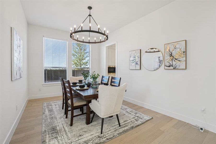 Dining room with light wood-type flooring and a chandelier Dining room with light wood-type flooring and a chandelier
