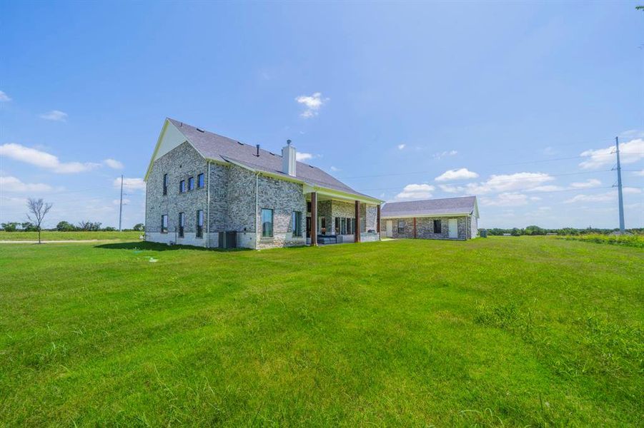 Back of property featuring a lawn and brick siding Back of property featuring a lawn and brick siding