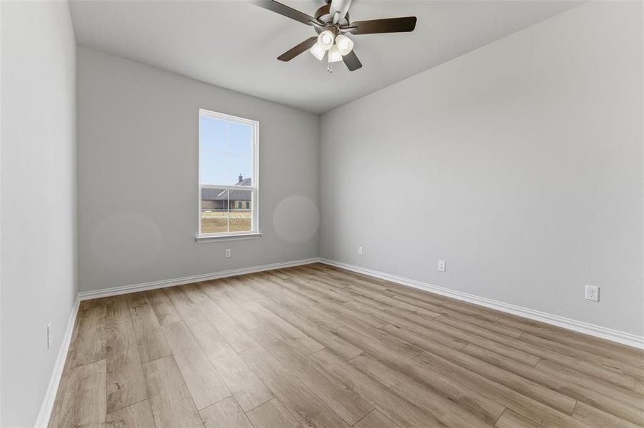 Empty room with a ceiling fan and light wood-style flooring