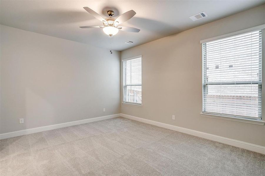 Empty room featuring baseboards, a ceiling fan, visible vents, and light colored carpet