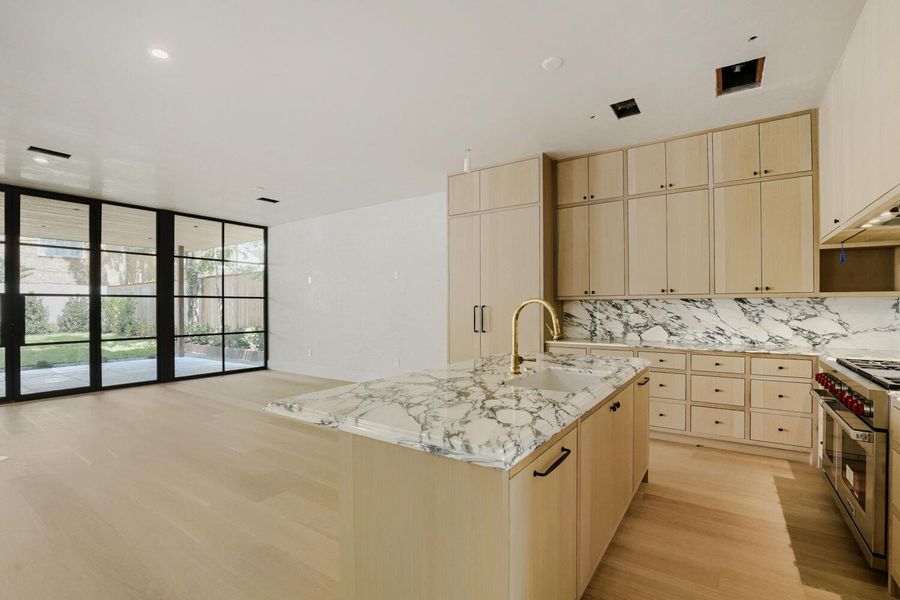 An inviting kitchen with a central island and a beautiful marble countertop, complemented by light wood cabinetry.