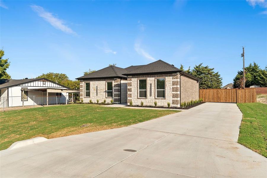 View of front facade featuring concrete driveway, a shingled roof, stone siding, and brick siding