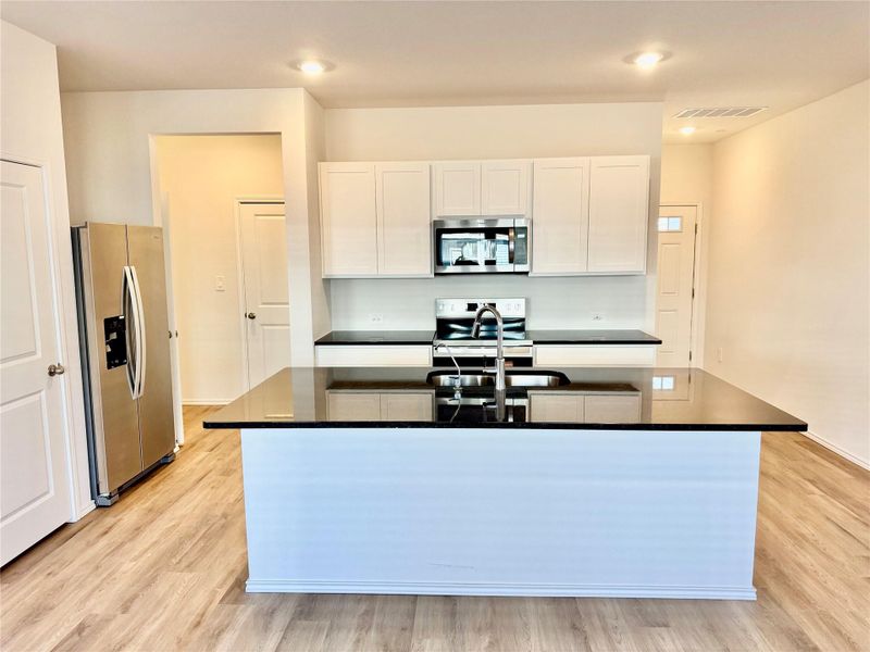 Kitchen with white cabinetry, stainless steel appliances, light wood-style flooring, a center island with sink, and recessed lighting