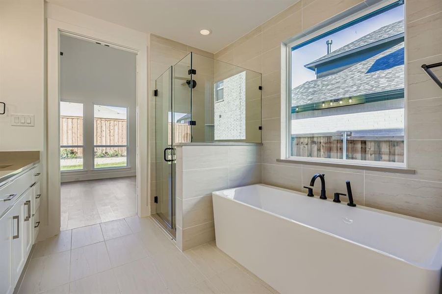Bathroom with a soaking tub, vanity, a shower stall, and light tile patterned floors