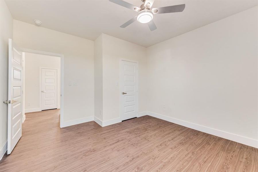 Empty room with ceiling fan and light hardwood / wood-style flooring