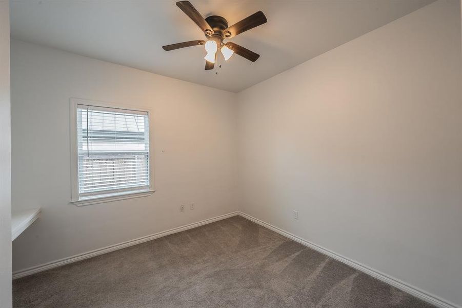 Spare room featuring dark carpet and a ceiling fan Spare room featuring dark carpet and a ceiling fan