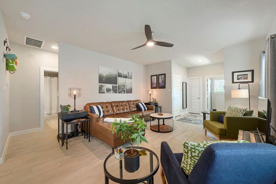 Natural light illuminates a modern living space featuring a brown leather sectional and light-toned flooring. Natural light illuminates a modern living space featuring a brown leather sectional and light-toned flooring.