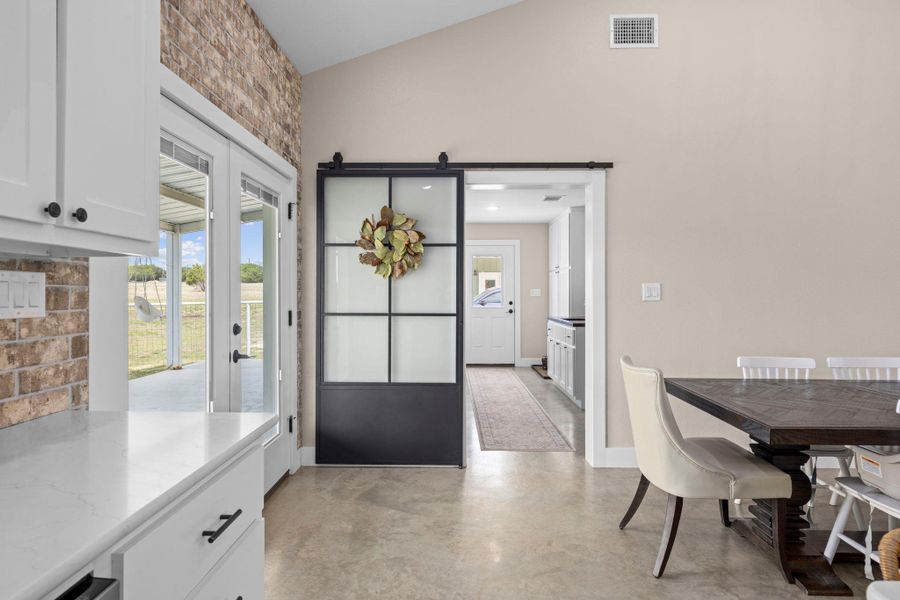 Dining room featuring a barn door, concrete floors, and vaulted ceiling