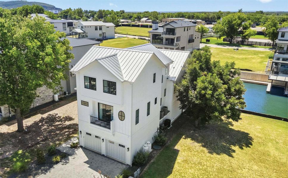 An aerial view captures the home's striking architecture and serene waterfront location, complete with an attached boat dock. An aerial view captures the home's striking architecture and serene waterfront location, complete with an attached boat dock.