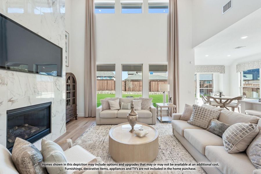 Living room with two-story ceiling, marble fireplace, wall-mounted TV, and large windows overlooking backyard Living room with two-story ceiling, marble fireplace, wall-mounted TV, and large windows overlooking backyard