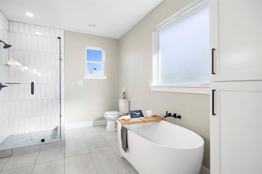 Bathroom featuring toilet, tile patterned flooring, and separate shower and tub