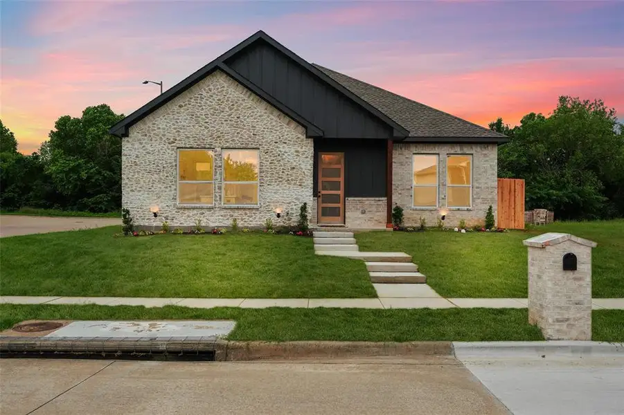 Contemporary facade featuring light-toned brick, dark vertical siding, and a dark shingle roof