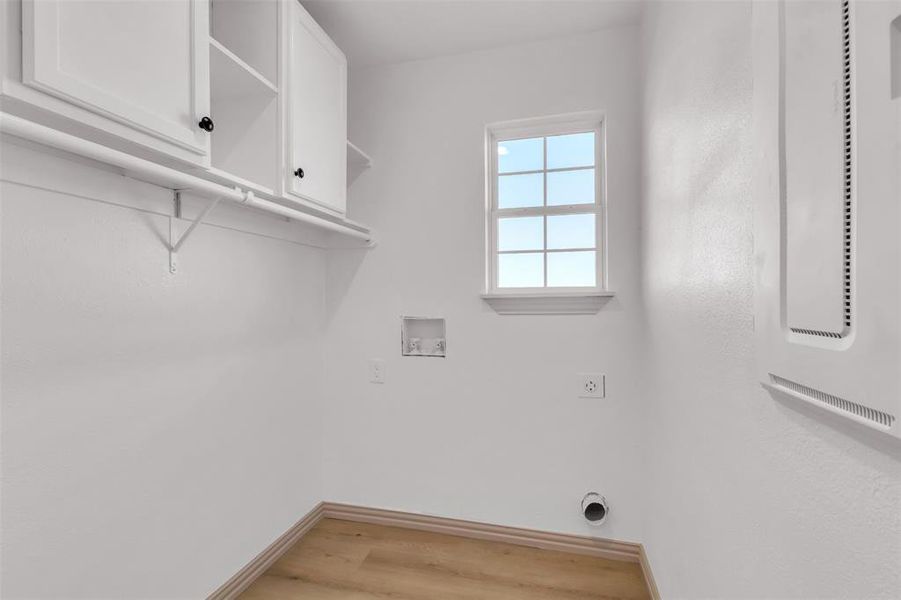 Laundry area featuring hookup for a washing machine, electric dryer hookup, cabinet space, light wood-style floors, and a heating unit Laundry area featuring hookup for a washing machine, electric dryer hookup, cabinet space, light wood-style floors, and a heating unit