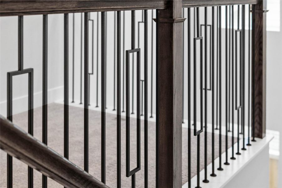 Modern living space featuring a stunning open-concept staircase with a dark wood handrail and sleek, geometric wrought iron balusters.