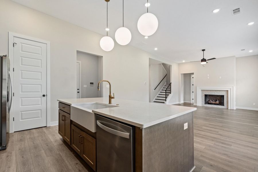 Kitchen island featuring a farmhouse sink, gold-finish faucet, and integrated dishwasher Kitchen island featuring a farmhouse sink, gold-finish faucet, and integrated dishwasher