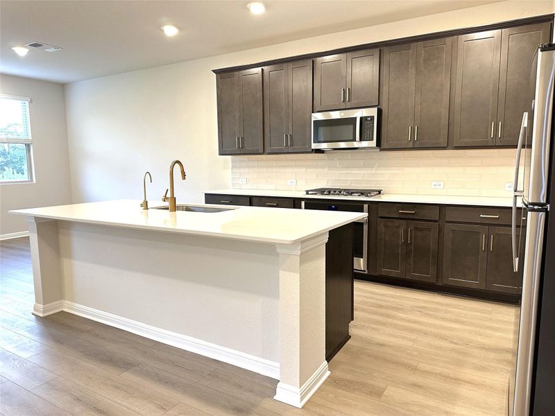 Kitchen with appliances with stainless steel finishes, a sink, light luxury vinyl plank floors, backsplash, and recessed lighting