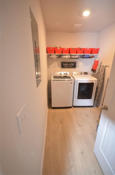 Laundry area with light wood-style flooring, separate washer and dryer, and electric panel Laundry area with light wood-style flooring, separate washer and dryer, and electric panel