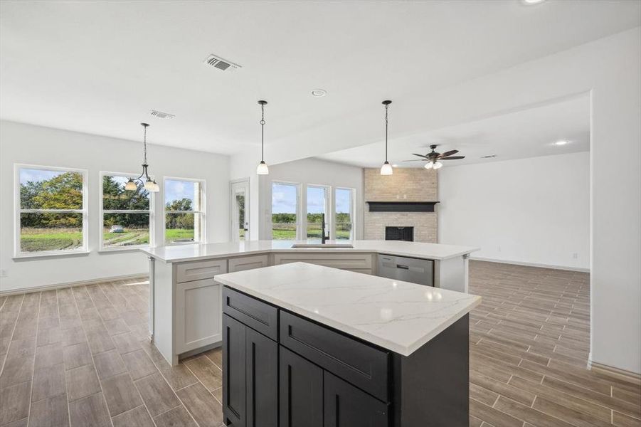 Kitchen with a center island, white cabinets, hanging light fixtures, a large fireplace, and light hardwood / wood-style floors