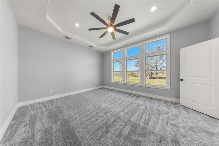 Empty room with a tray ceiling, light carpet, ceiling fan, and recessed lighting Empty room with a tray ceiling, light carpet, ceiling fan, and recessed lighting
