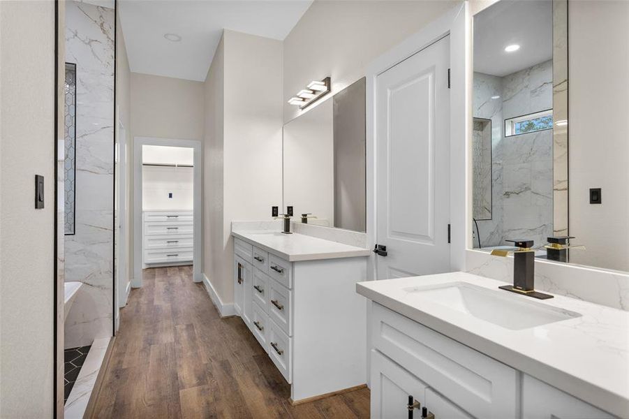 Welcome to your Primary Bath. In this photo you can see your two separate vanities with tons storage space and to the left a sneak peek of the soaker tub on the left and the primary closet in the rear.