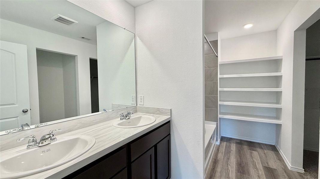 Primary bath features dual sinks and a convenient linen storage cabinet.