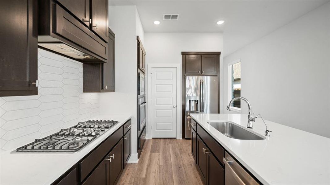 You will love the details of this kitchen! It features built-in SS appliances, a large single basin sink with sleek faucet, reverse osmosis under the sink, SS cabinet hardware, walk-in pantry, quartz counters, geometric textured white backsplash, and LED overhead lighting.