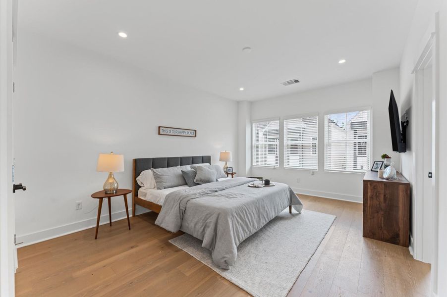 This spacious second-floor primary bedroom exudes modern elegance with its sleek engineered wood flooring that adds warmth and texture underfoot. Soaring high ceilings amplify the sense of openness, allowing natural light to cascade in and highlight the room’s architectural charm. Whether styled with minimalist furnishings or layered with cozy accents, the space offers a serene retreat elevated by its refined finishes and elevated vantage point.