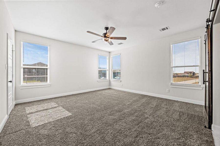 Carpeted spare room with a barn door and ceiling fan