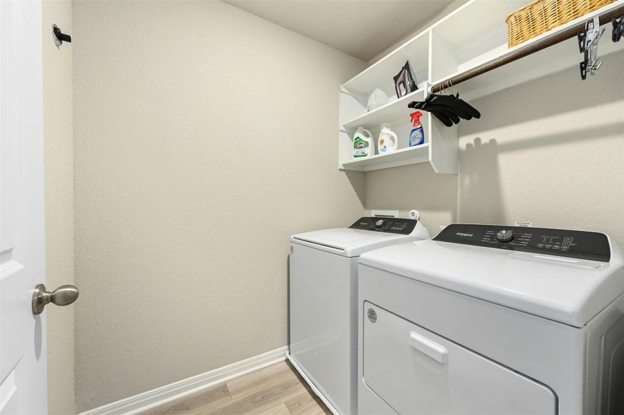 Laundry area with washer and clothes dryer and light hardwood / wood-style floors