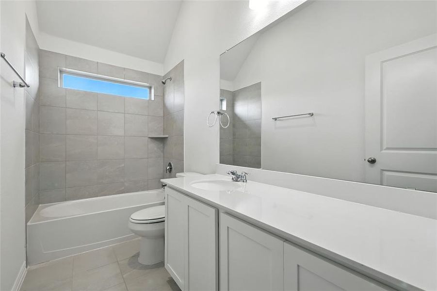 Full bath with vanity, shower / bathtub combination, lofted ceiling, and light tile patterned floors