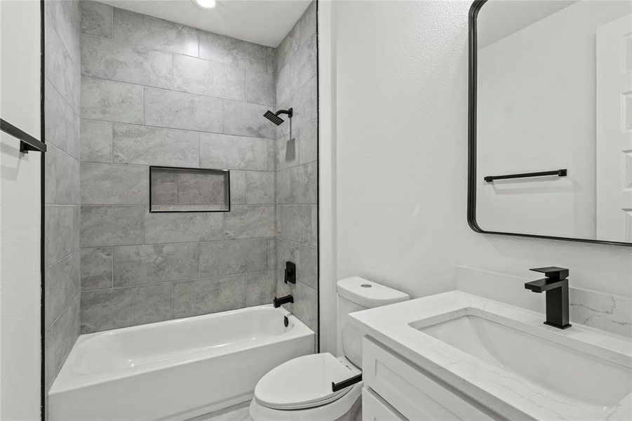 Full bathroom featuring toilet, vanity, and tiled shower / bath