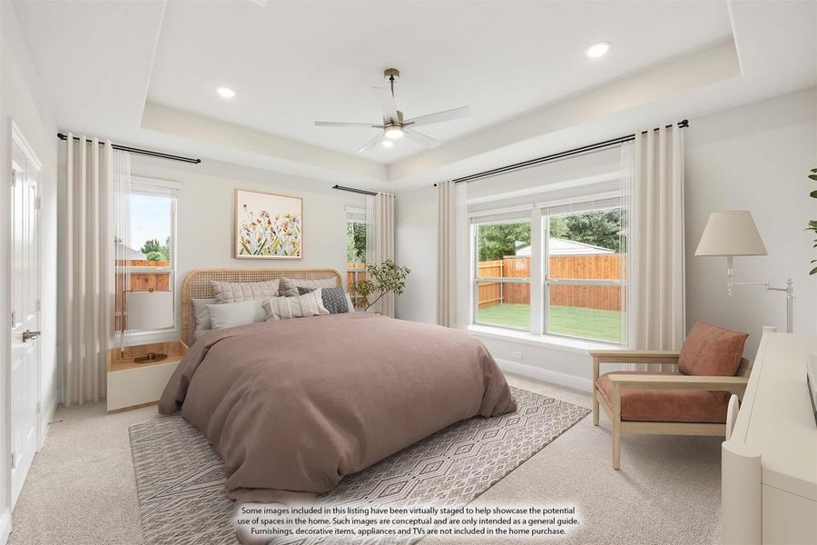 Bedroom with tray ceiling, ceiling fan, carpet flooring, and large windows overlooking backyard