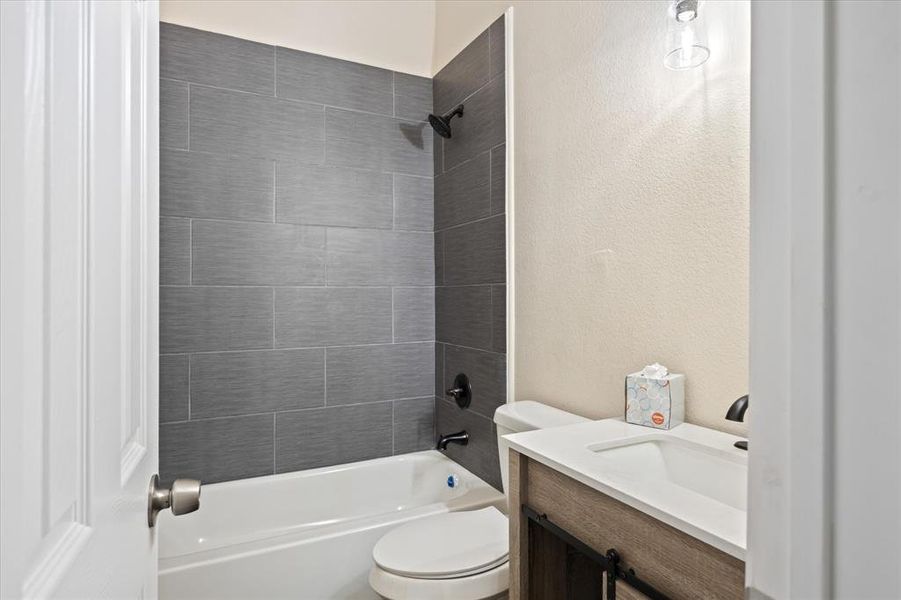 Full bathroom featuring tiled shower / bath, vanity, and toilet