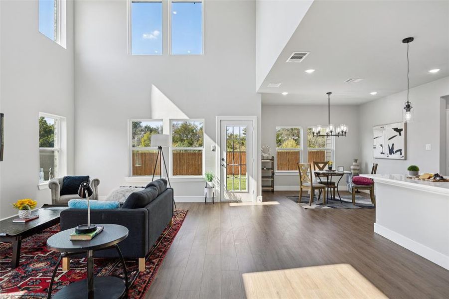 Living area featuring dark wood-style floors, a high ceiling, a chandelier, and recessed lighting