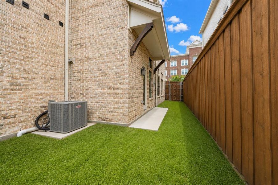 Private outdoor space featuring artificial turf, a wood privacy fence, and a concrete patio