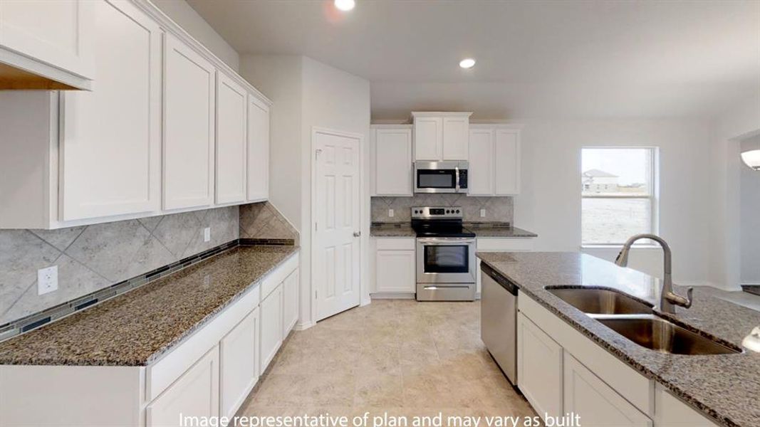 Kitchen featuring white cabinetry, granite countertops, stainless steel appliances, a tile backsplash, and a central island with a double basin sink Kitchen featuring white cabinetry, granite countertops, stainless steel appliances, a tile backsplash, and a central island with a double basin sink
