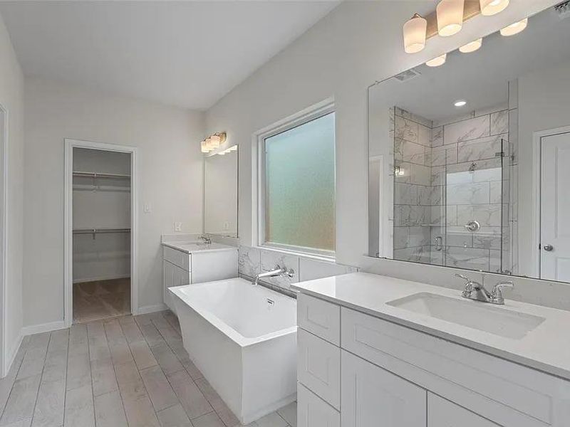 Luxurious primary bath showcasing a spacious soaking tub, elegant double vanity, and a grand walk-in shower.