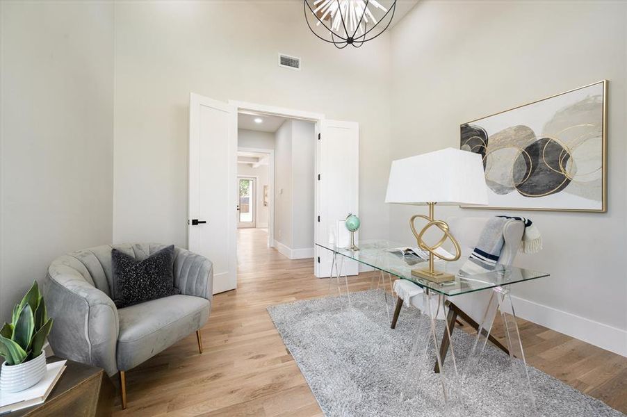 Sitting room with a towering ceiling and light hardwood / wood-style flooring