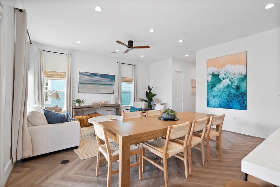 This bright and inviting living room combines coastal charm with modern comfort. A high wood-beamed ceiling with a sleek fan draws the eye upward, while natural light filters through the surrounding windows, illuminating soft textures and warm, neutral tones. This bright and inviting living room combines coastal charm with modern comfort. A high wood-beamed ceiling with a sleek fan draws the eye upward, while natural light filters through the surrounding windows, illuminating soft textures and warm, neutral tones.