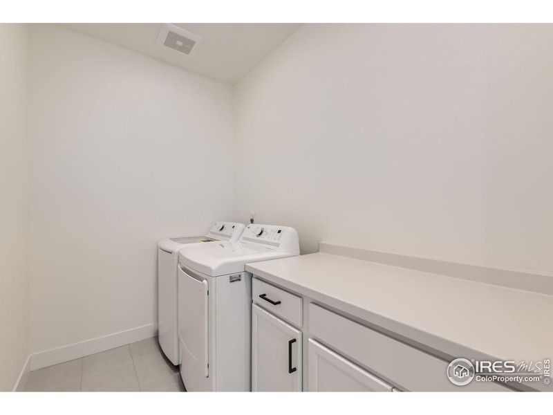 The upper level laundry room has plenty of room, includes the new washer and dryer, folding counter, tile floor.