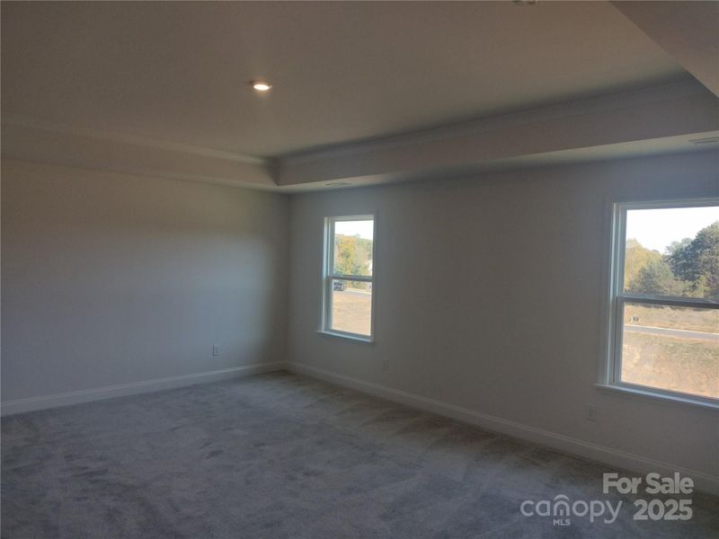 Spacious Primary Suite Features Plenty of Light, Wallspace, & a Tray Ceiling- Representative Photo