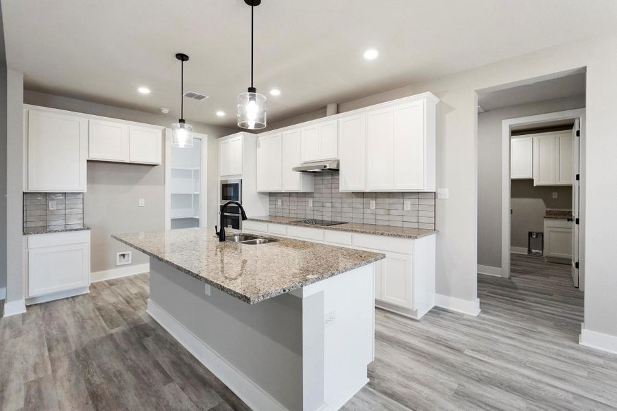 Kitchen featuring decorative backsplash, light stone counters, light wood-style floors, white cabinetry, and recessed lighting