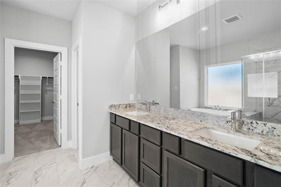 This primary bathroom is definitely move-in ready! Featuring stained cabinets with granite countertops, spacious walk-in closet with shelving, high ceilings, custom paint, sleek modern finishes.