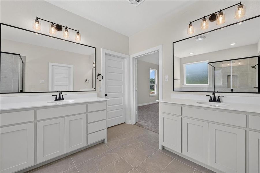 Bathroom featuring dual vanities with white cabinetry, white countertops, and black fixtures Bathroom featuring dual vanities with white cabinetry, white countertops, and black fixtures