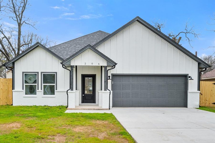 Modern inspired farmhouse featuring a garage, driveway, roof with shingles, fence, and board and batten siding