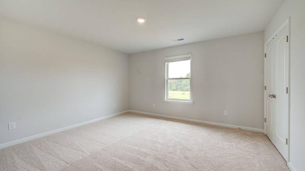 Secondary bedroom with carpet flooring and window providing natural light in the Meridian II at Brighton in Locust Grove, GA.